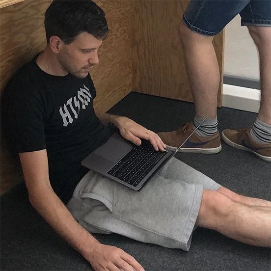 ein epunk sitzt mit seinem Laptop unter einem Tisch und arbeitet